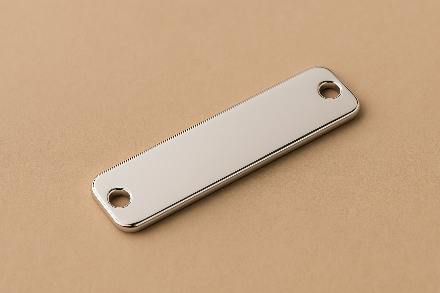 Plaque rectangulaire en argent rhodié de 4,5 × 1,2 cm avec deux trous pour cordon, posée sur un fond beige doux, montrant sa surface lisse et brillante.