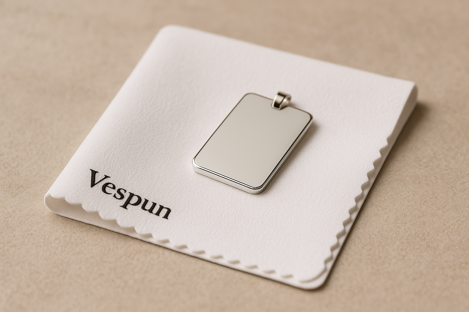 Plaque rectangulaire en argent rhodié posée sur un tissu de nettoyage Vespun blanc, sur fond beige, montrant la finition brillante et propre du bijou.